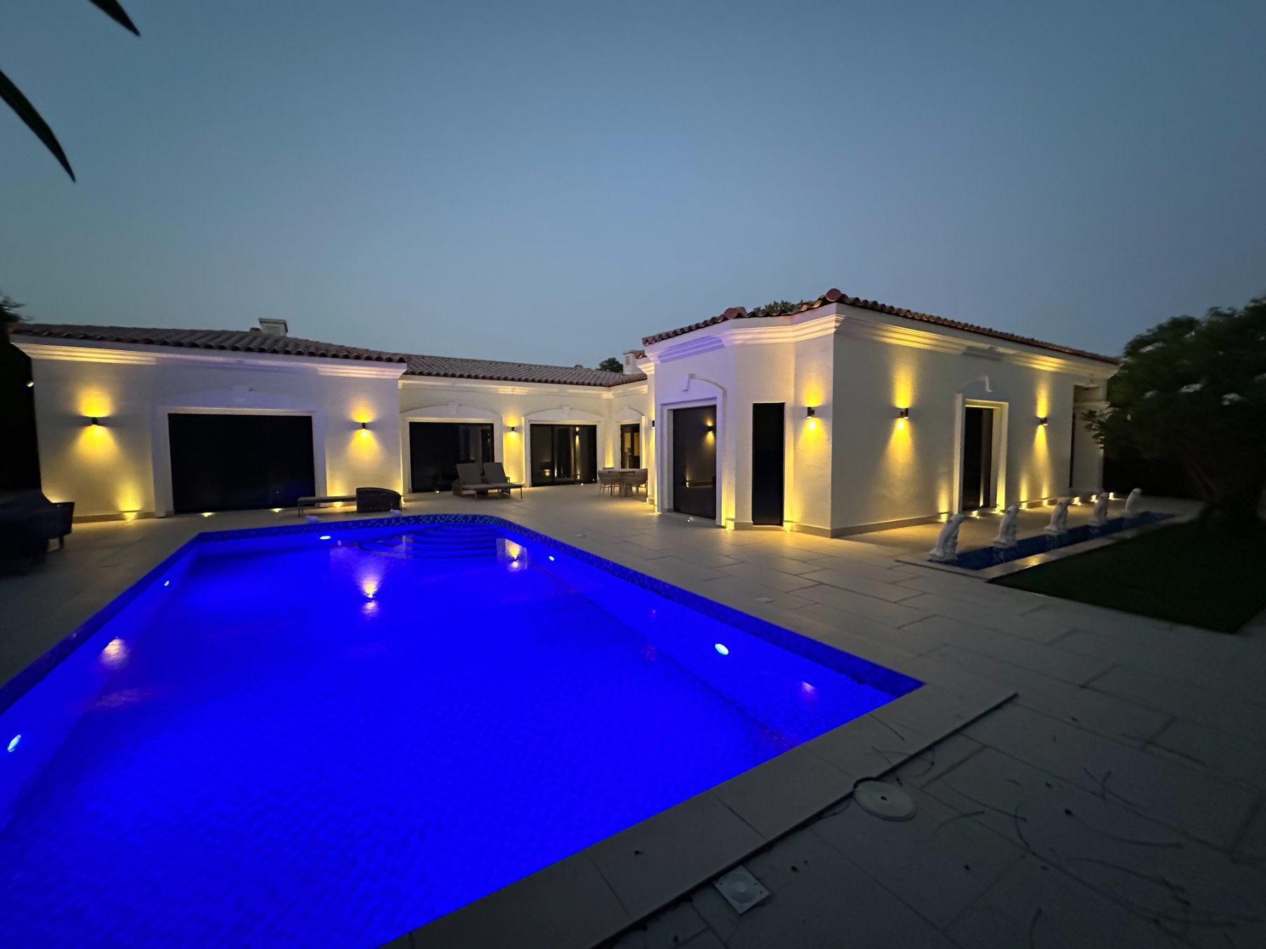 The same villa and pool lit at dusk